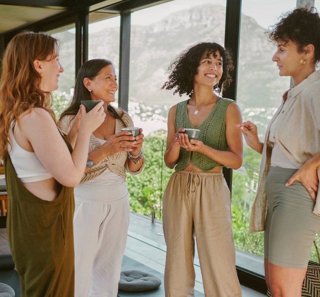 Cuatro mujeres conversando con una taza en la mano