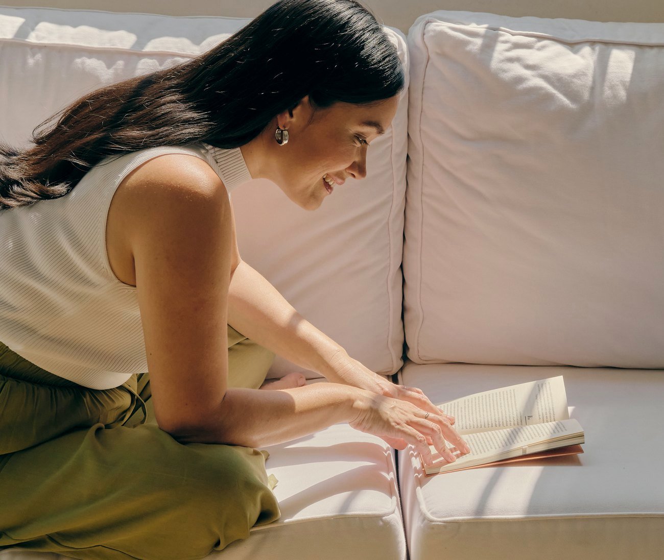 Mujer tumbada en un sofá leyendo un libro